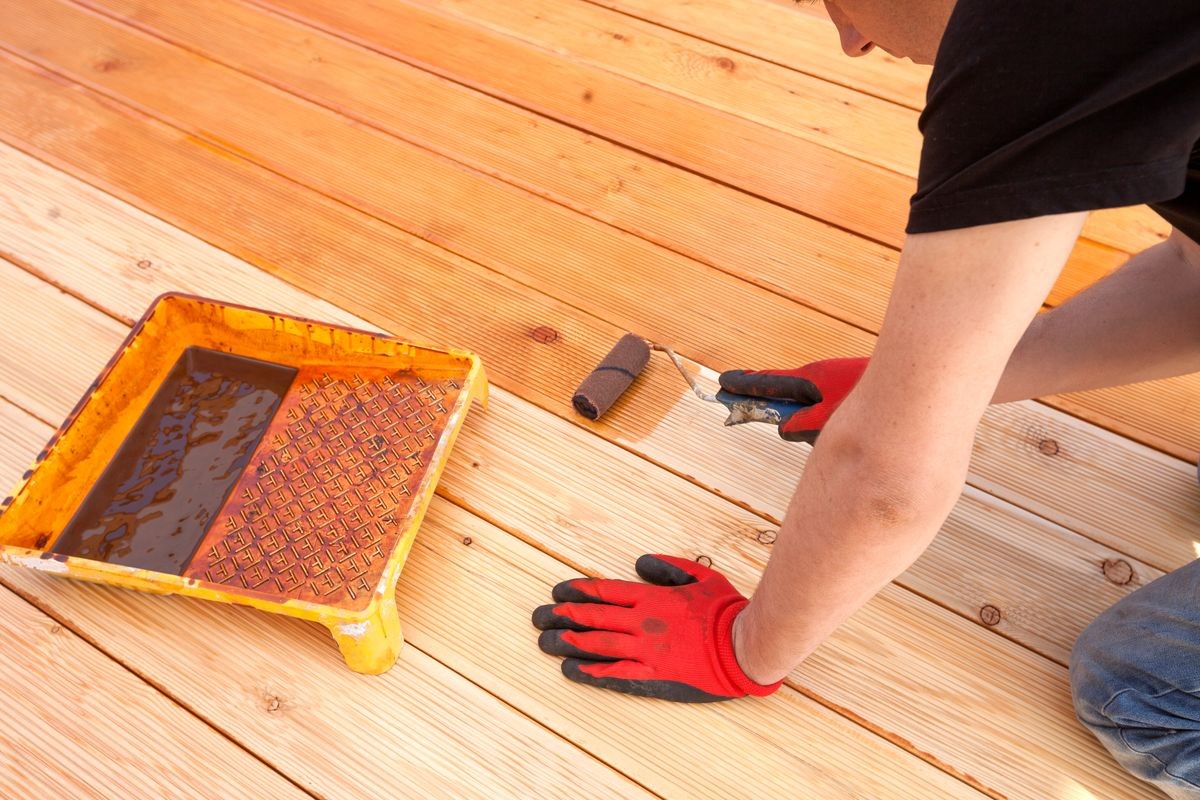 Painting a terrace board impregnation water proofing. Carpenter painting wood.