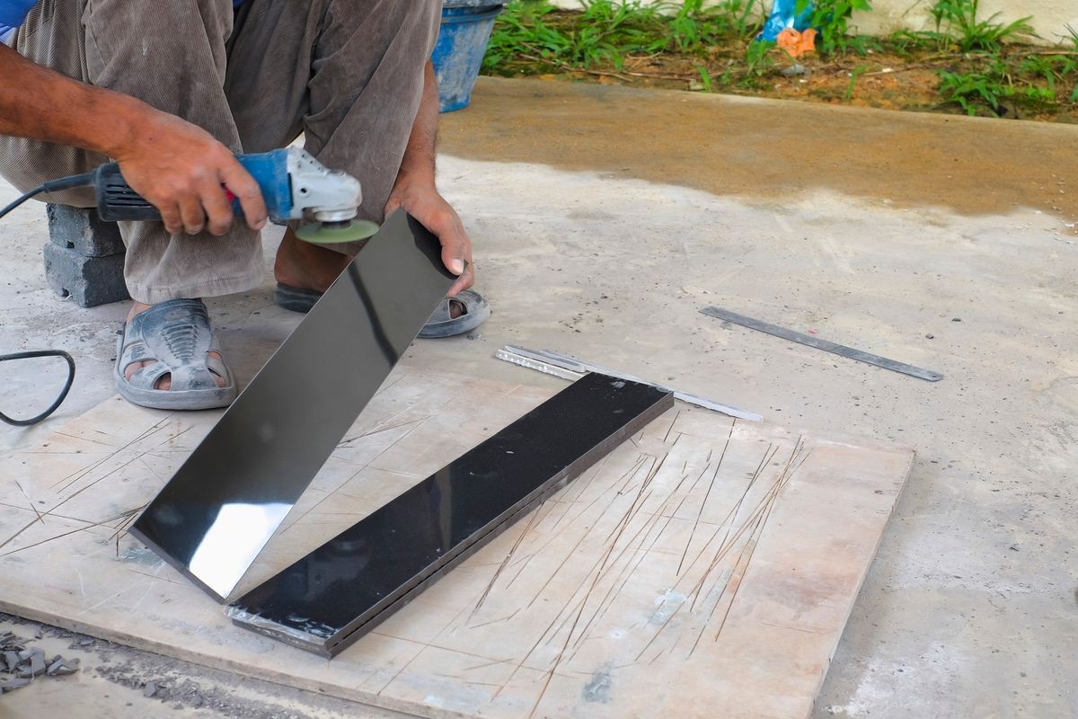 Worker cutting floor tiles with angle grinder  at construction site. Kitchen renovation  and improvement.