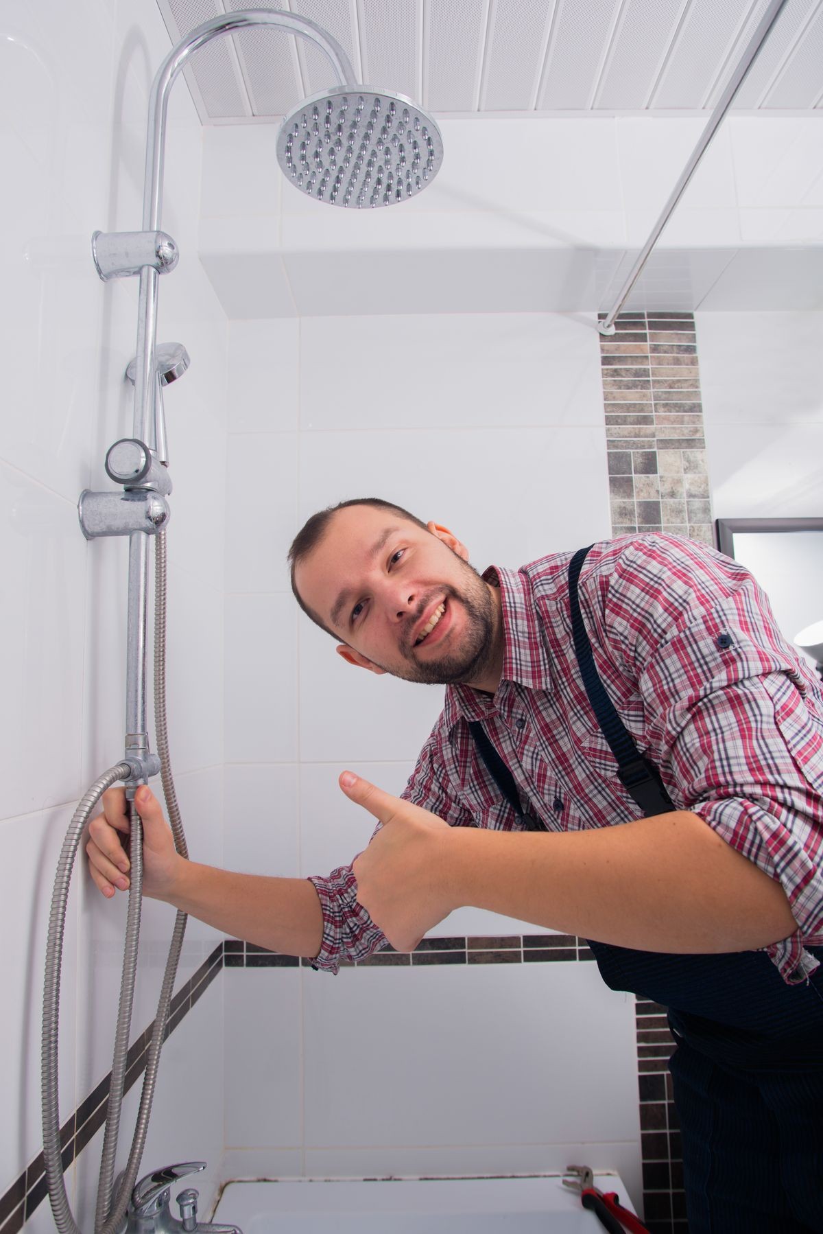 plumber repairing shower head in bathroom